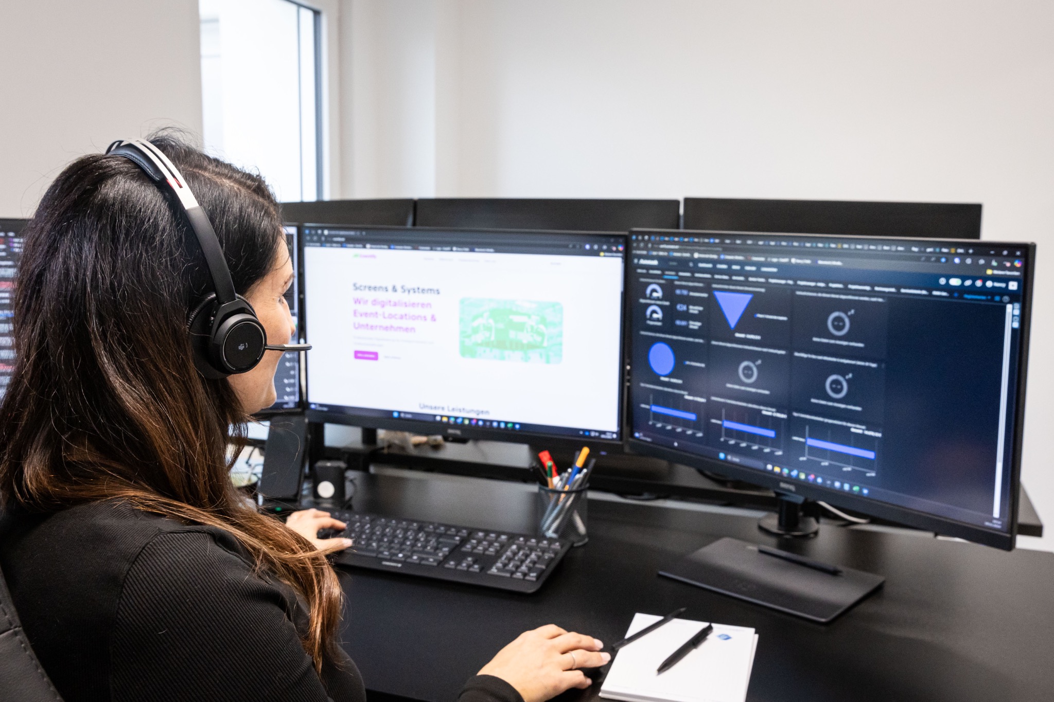 Mitarbeiterin der WMS Software GmbH an einem Arbeitsplatz mit mehreren Entwicklungs- und Monitoringansichten.